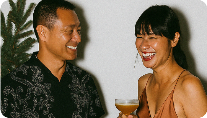 A couple smiling across the table holding drinks